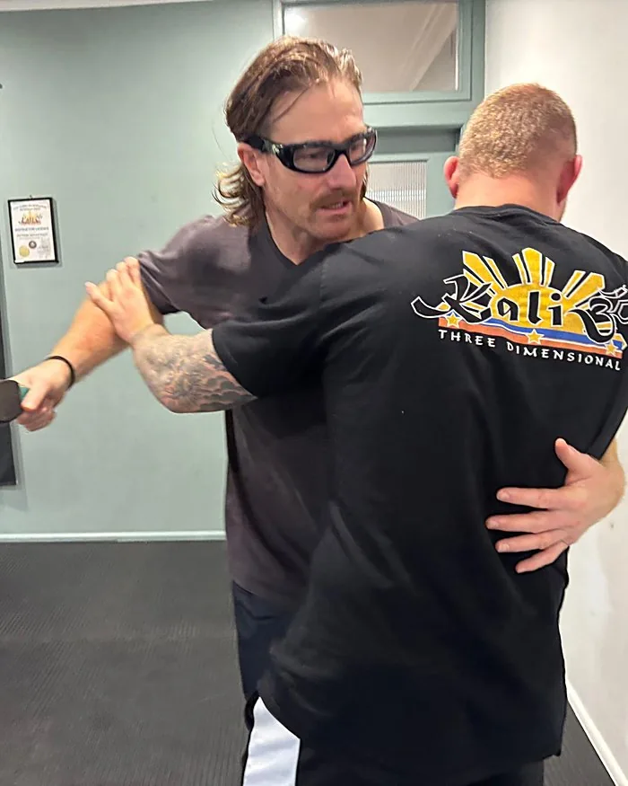 Senior Master Mark Day applying a shoulder-lock control technique on a training partner wearing a Kali 3D shirt